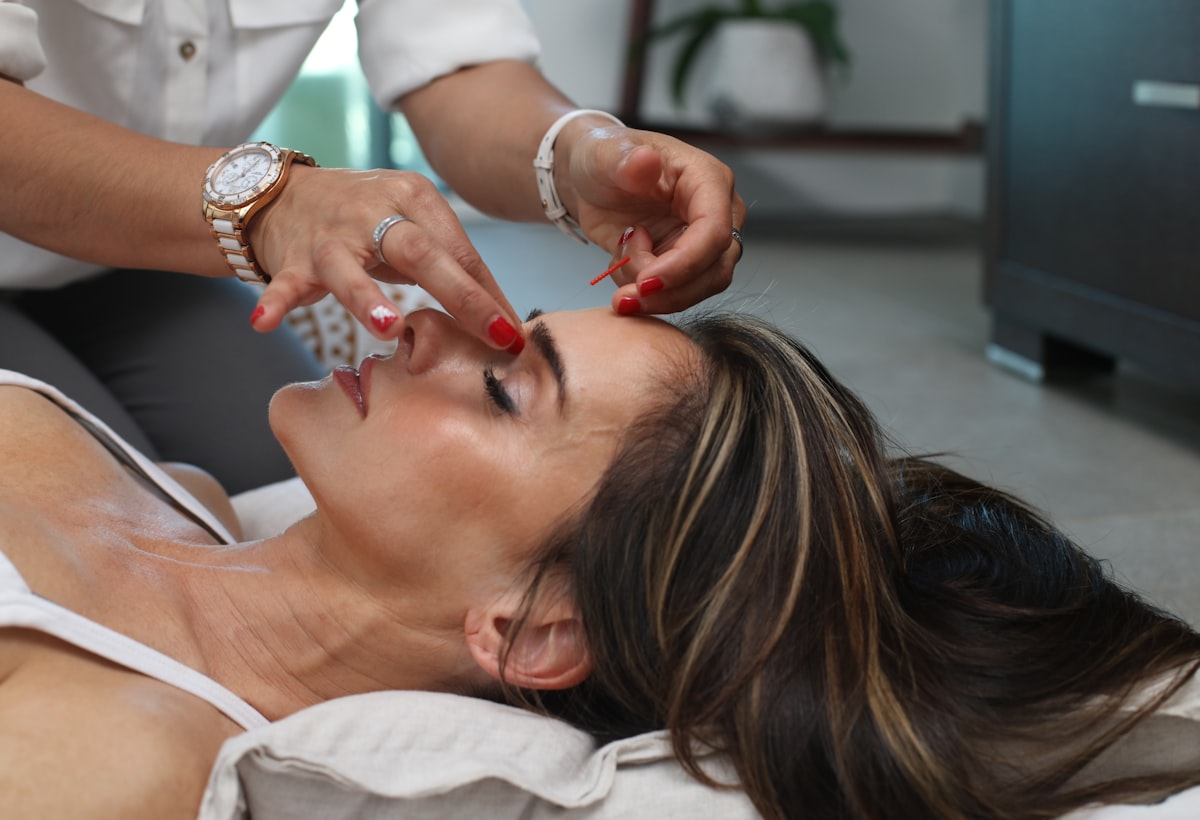 A practitioner performing a calm, precise facial treatment in a bright clinic